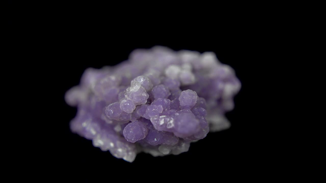 la rotación sin problemas de un mineral púrpura (ágata de uva) frente a un fondo negro
