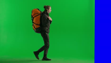 man hiking with large backpack on green screen