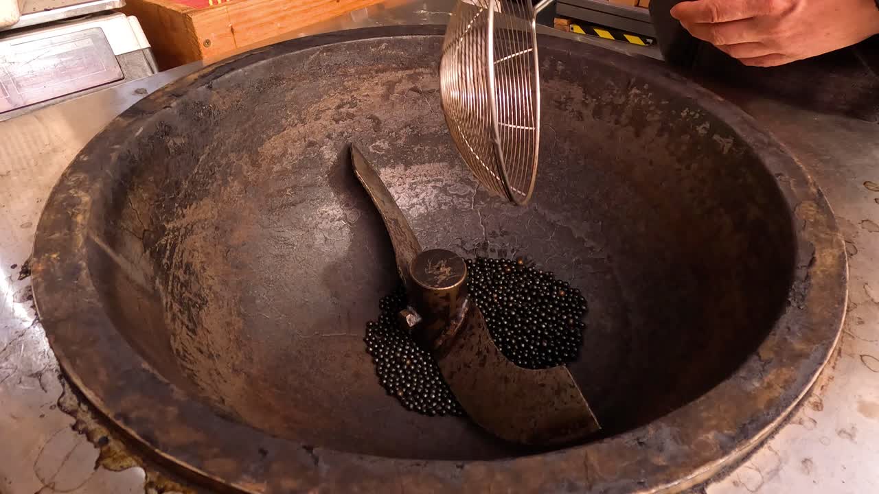 Mãos colocando pedras no fogão para castanhas