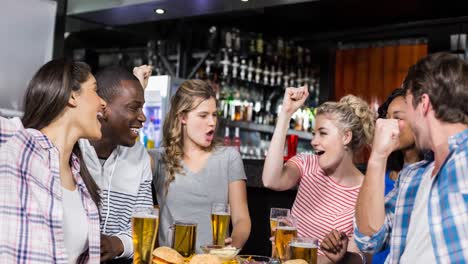 felices fans de deportes femeninos y masculinos diversos viendo el juego en el bar, animando y bebiendo