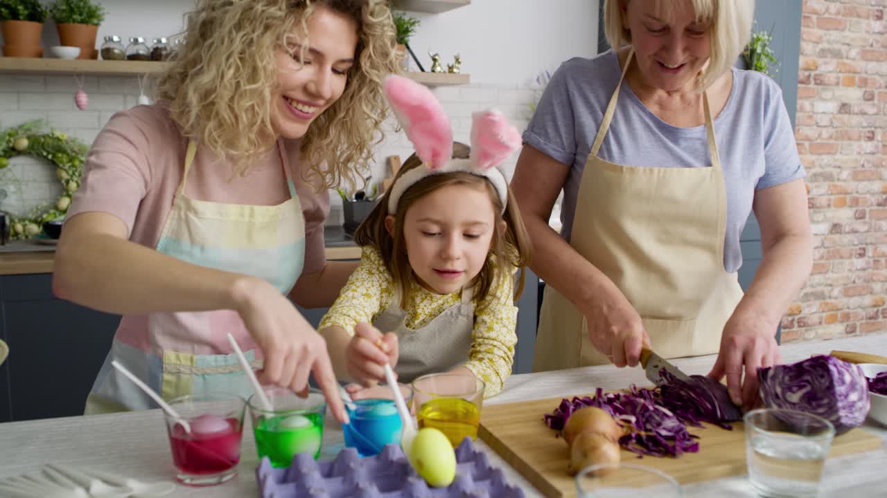 Video of three generation of women preparation Easter eggs together
