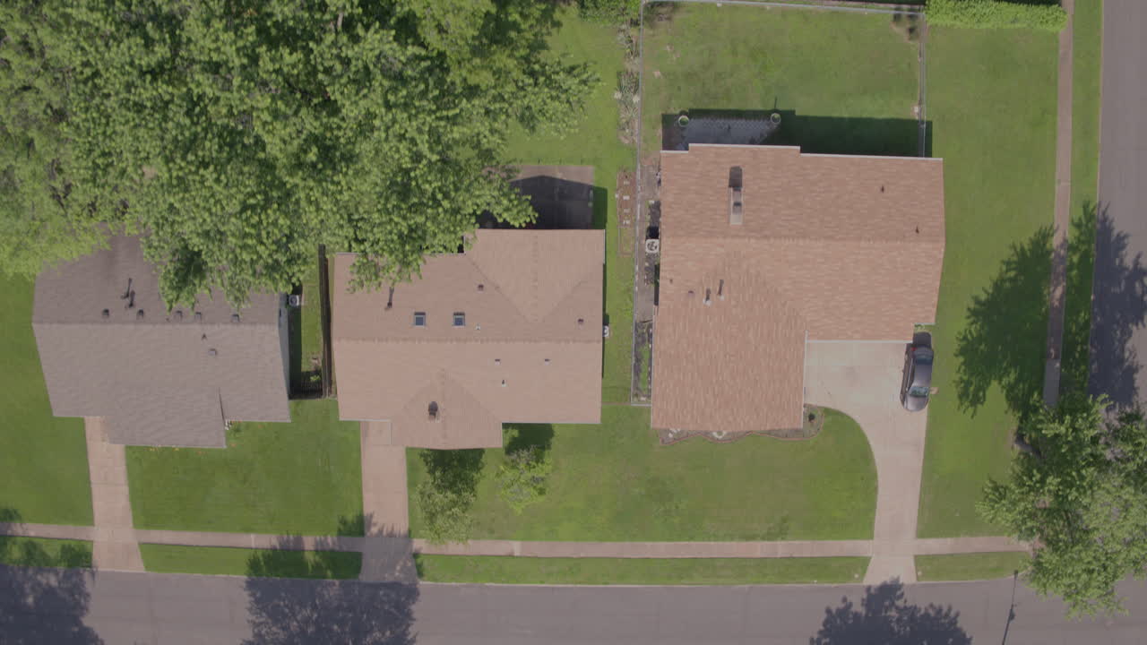 vista directa hacia abajo y tire hacia atrás sobre casas suburbanas, calles y árboles