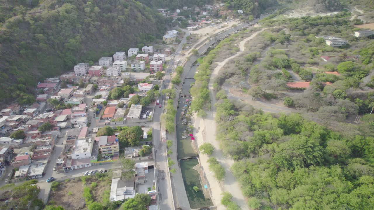 Camuri grande village near the river with lush greenery and buildings, aerial view