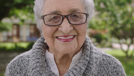 retrato de una anciana jubilada en el parque sonriendo feliz mirando a la cámara con gafas