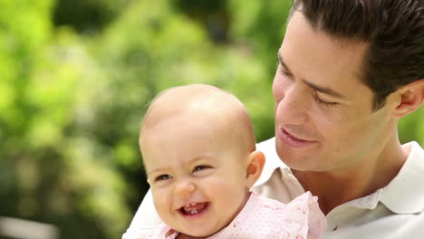 padre feliz sosteniendo a su niña en el parque