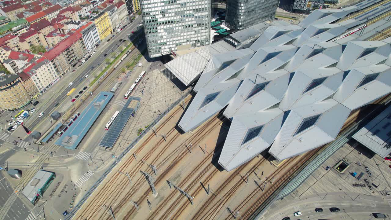 Wien HBF drone, Aerial Birds Eye View Of Train Tracks And Roof Structure At Vienna central train station with Pan up reveal Of Cityscape