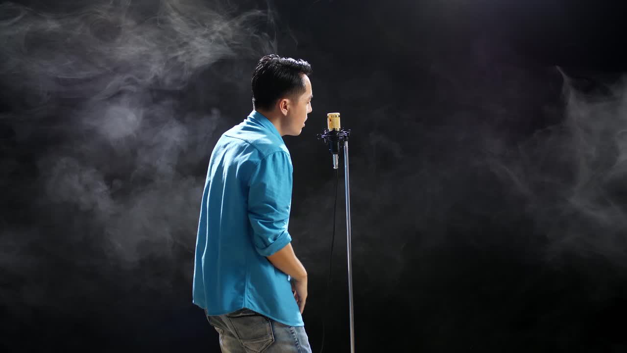 hombre cantando en el micrófono en el escenario con humo