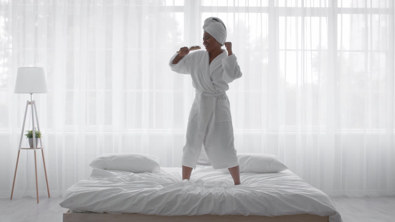 женщина танцует в халате на кровати.