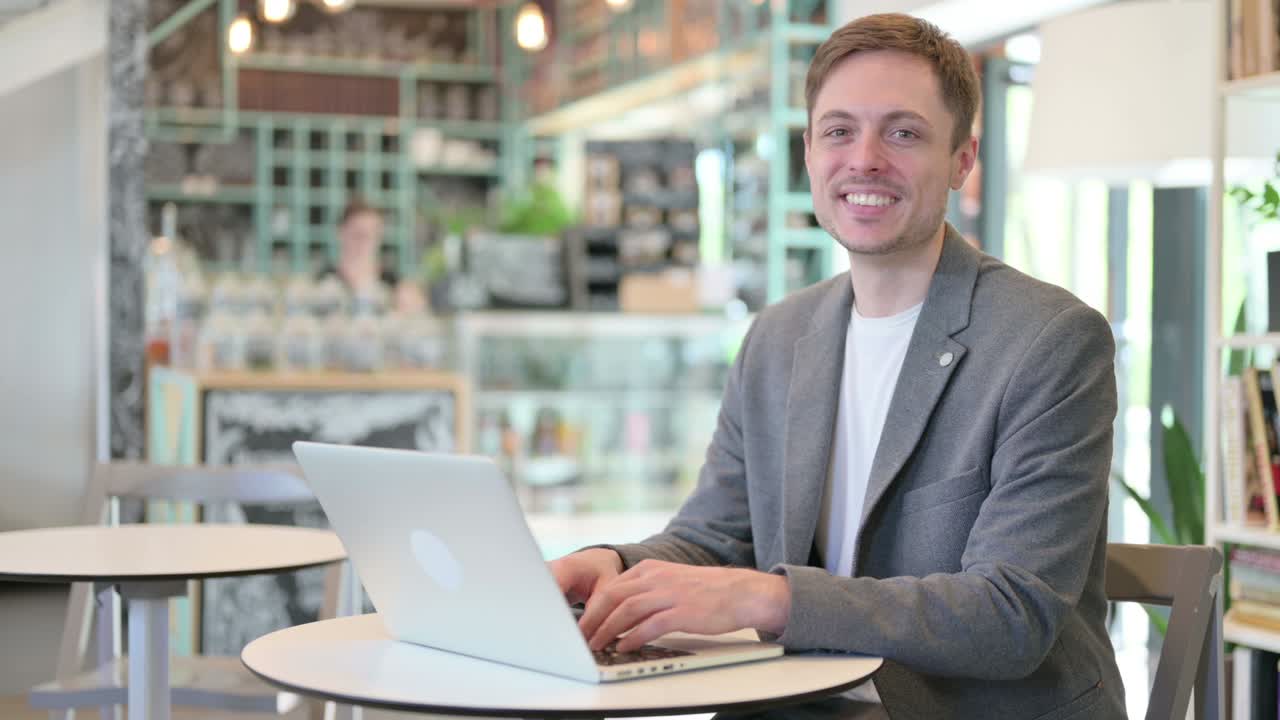 Young Businessman with Laptop Smiling at Camera