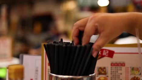 hand choosing chopsticks from a container