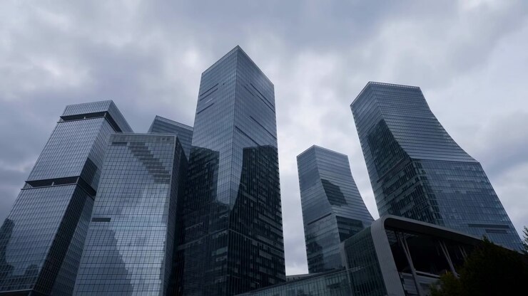 Arranha-céus de vidro sob nuvens de tempestade, fachadas refletivas dominam o distrito corporativo com ângulo baixo.
