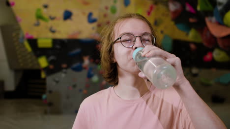 teenage boy drinking water in an indoor gym