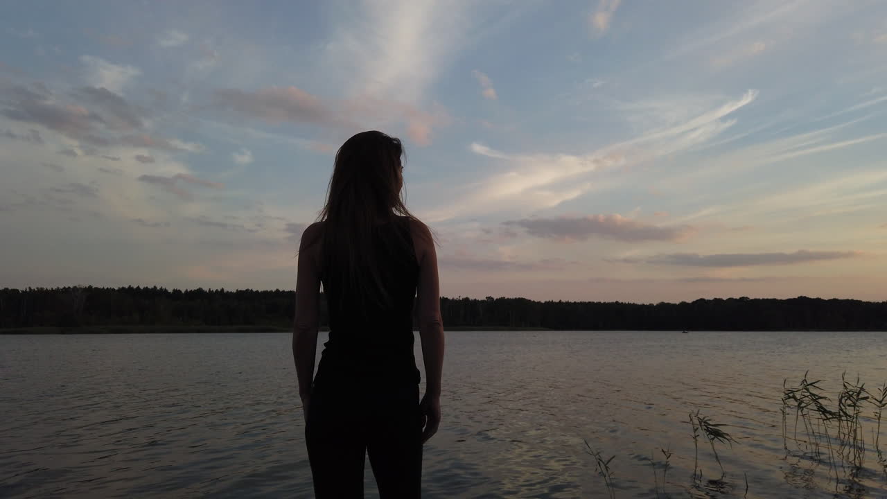 toma cinematográfica de una mujer en un pequeño muelle admira el maravilloso lago al atardecer