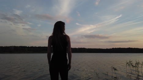 toma cinematográfica de una mujer en un pequeño muelle admira el maravilloso lago al atardecer