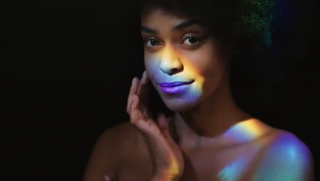 retrato colorido hermosa mujer afroamericana tocando el rostro con la mano acariciando la piel suave y saludable disfrutando del cuidado natural de la piel belleza con confianza en el fondo negro