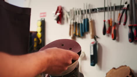craftsperson putting sandpaper discs on sander device