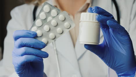 doctor in gloves shows pills and jar