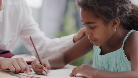 African-american-mother-and-daughter-sitting-and-table-and-doing-homework-together,-slow-motion