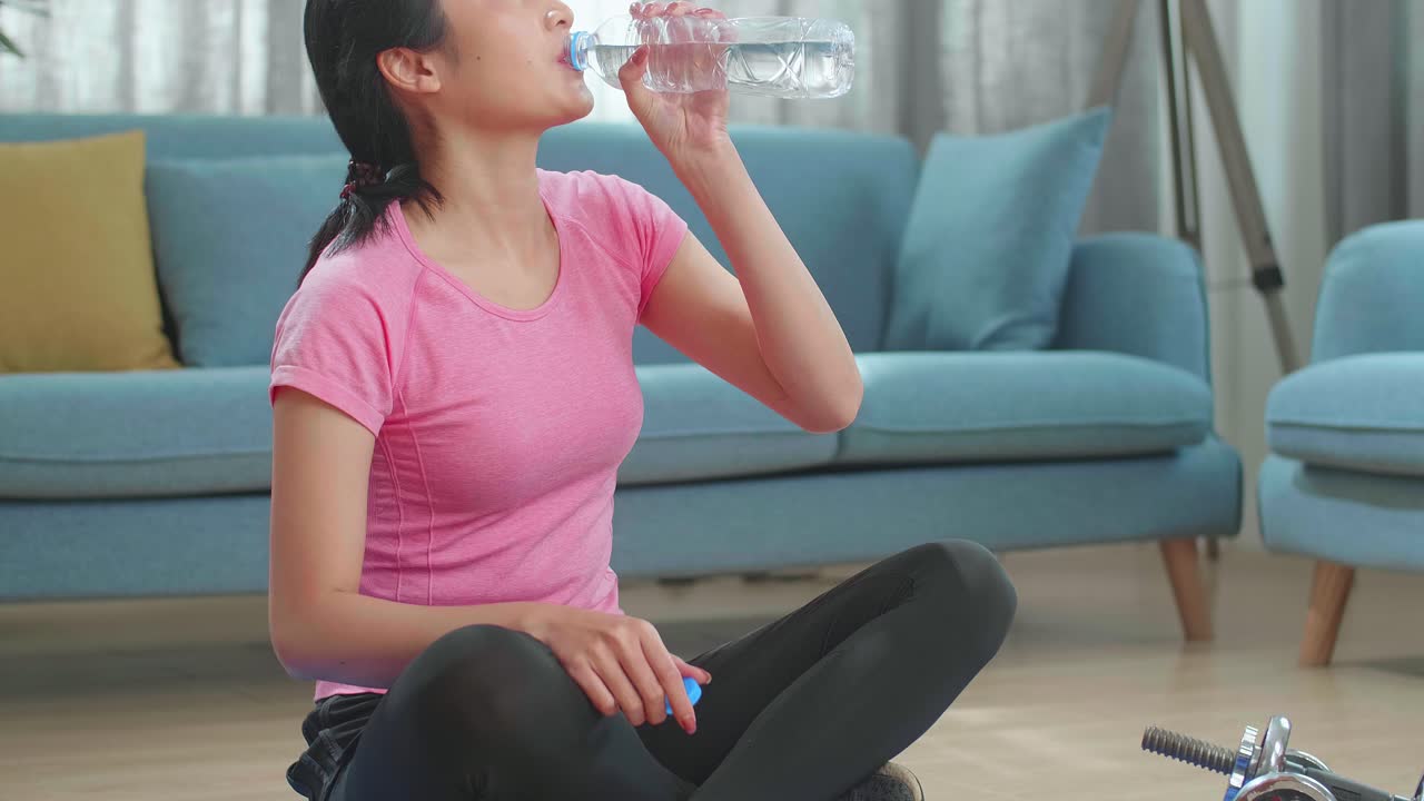 Young Asian Woman Drinking Water And Resting, Having Break After Doing Exercise At Home