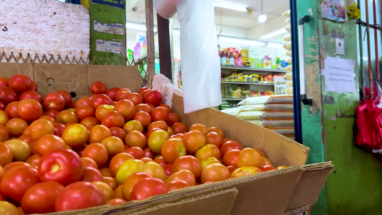 Low-angle camera pans over ripe tomatoes in bright indoor vegetable market with natural lighting