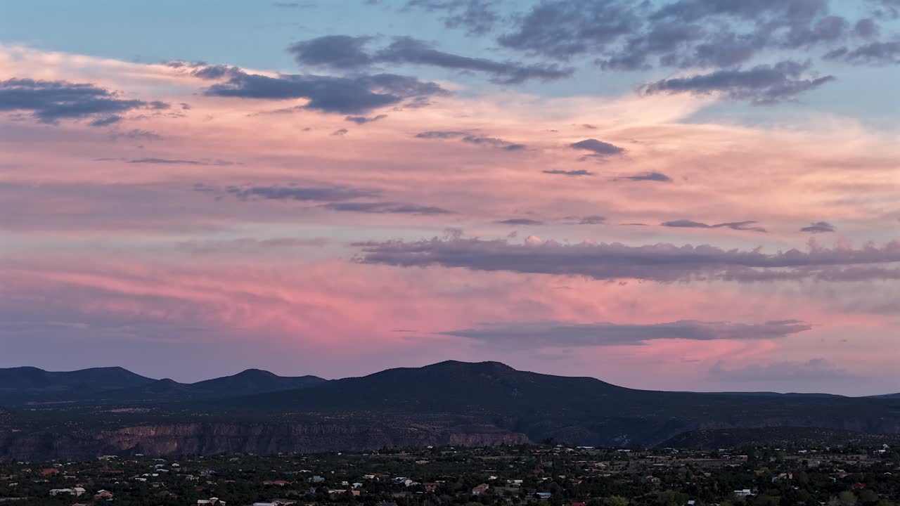 Un timelapse cinematografico in 4K con drone cattura una surreale montagna del sud-ovest mentre i colori del tramonto si spostano nel cielo. La luce vibrante e il movimento rapido creano uno sfondo naturale ultraterreno ed epico.