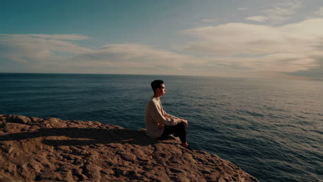 person sitting on a cliff overlooking the ocean