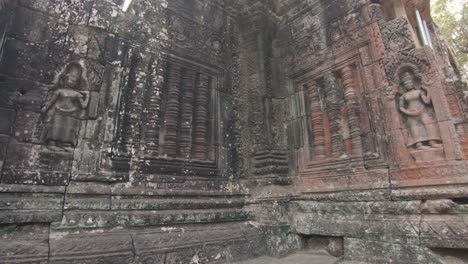 backwards pan away from a richely detailed wall that's part of the ruins in angkor wat