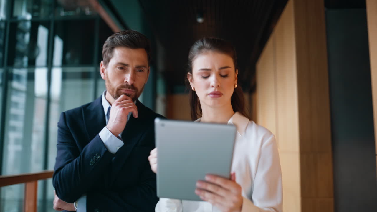 Woman secretary showing tablet to businessman walking office corridor closeup