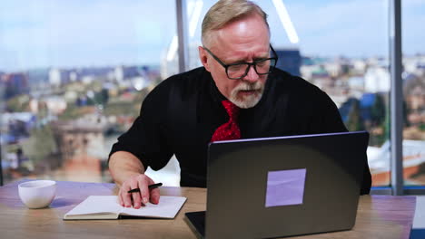 Concerned Caucasian businessman looks at laptop screen. Man looks worried, having trouble with computer. Blurred backdrop.