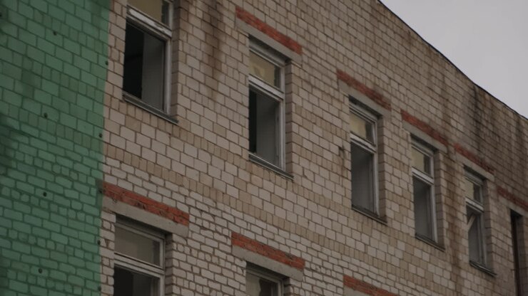Edificio de ladrillo abandonado con ventanas rotas y escalera de incendios