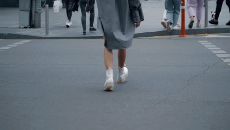 piernas de chicas cruzando la calle en el cruce de peatones en la calle del centro de la ciudad.