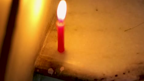 lighted candle flickering in dark environment from flat angle