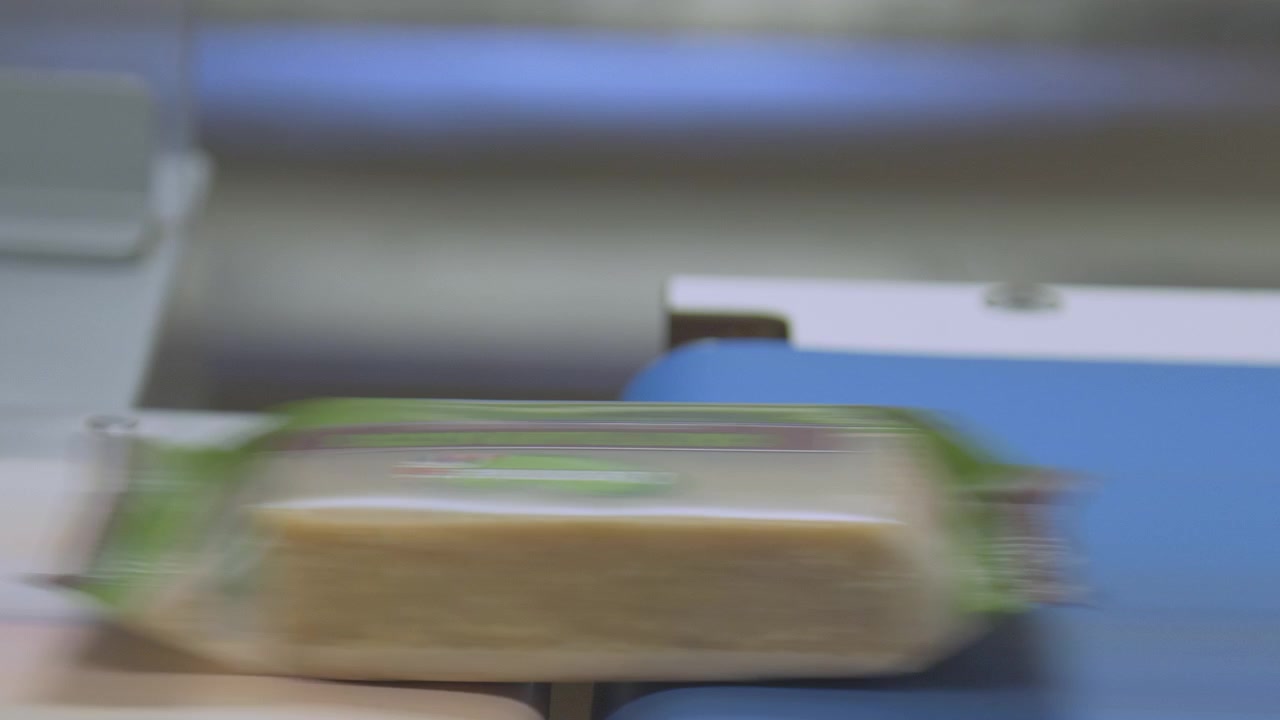 Packaged flapjack bars move along a conveyor belt at the end of a production line