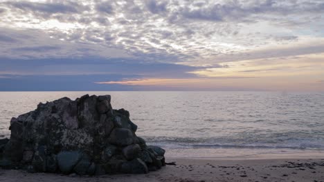 Beautiful-vibrant-sunset-time-lapse-of-fast-moving-clouds-over-the-Baltic-sea-at-Liepaja,-dark-storm-clouds,-old-fortification-ruins-in-foreground,-calm-sea,-copy-space,-low-angle-wide-shot,-slow-zoom