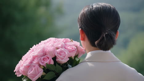 a person from behind holding a large bouquet of pink roses