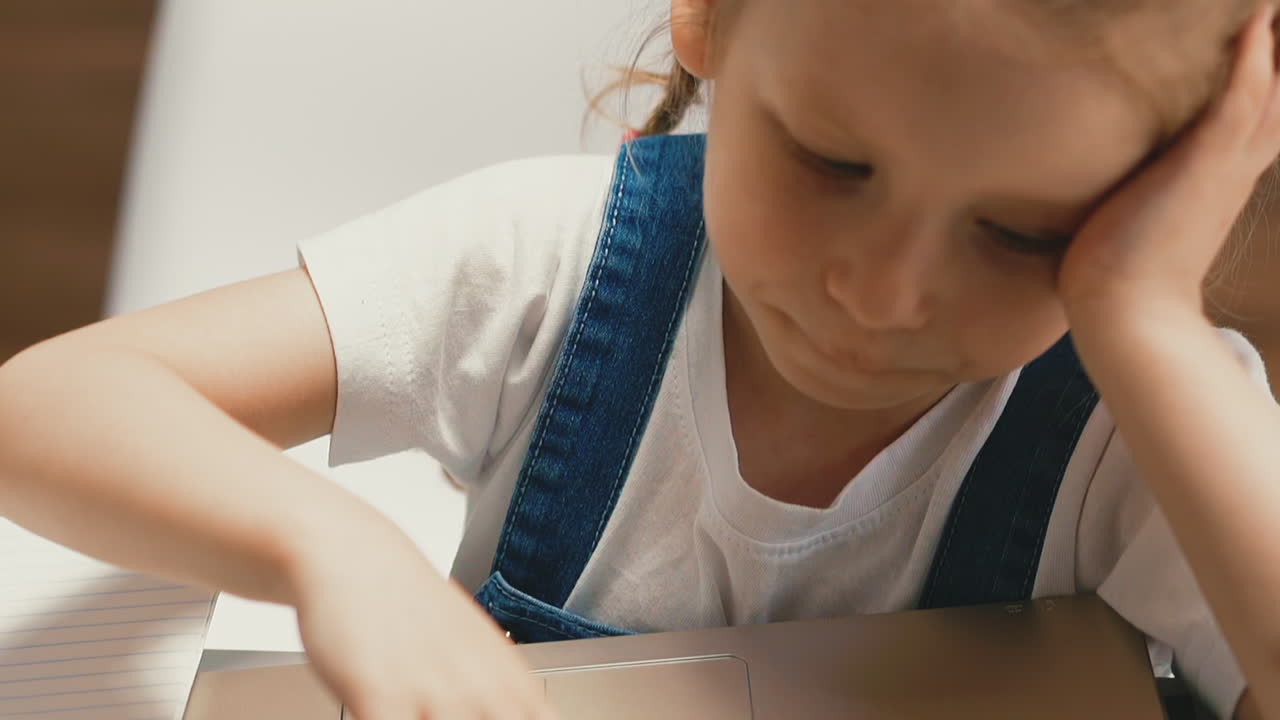 예쁜 소녀가  ⁇ 에서 테이블에 앉아 노트북으로 놀고 있습니다.