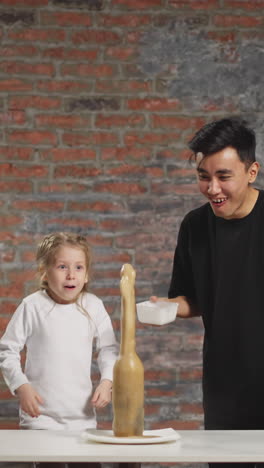 young asian man pours reagent into bottle and little girl runs away scared of erupting soda drink jet at scientific experiment in lab slow motion