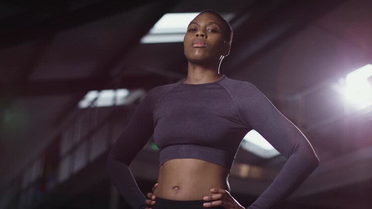 Studio-Porträt einer Frau in Sportkleidung, stehend im Fitnessstudio