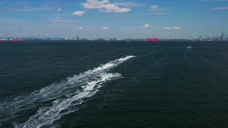 aerial chase of a group of jet ski riders on the waters between brooklyn - staten island, new york, moving towards new york city and the horizon