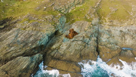 rusty shipwreck on rocky coastline