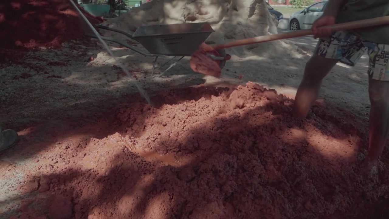 Slow motion of a worker mixing clay and sand with a shovel. Preparation of natural material for a sustainable and ecological building