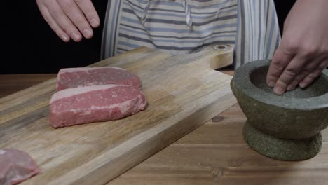 chef puts salt on new york steak from a mortar with his hands, for argentine barbecue