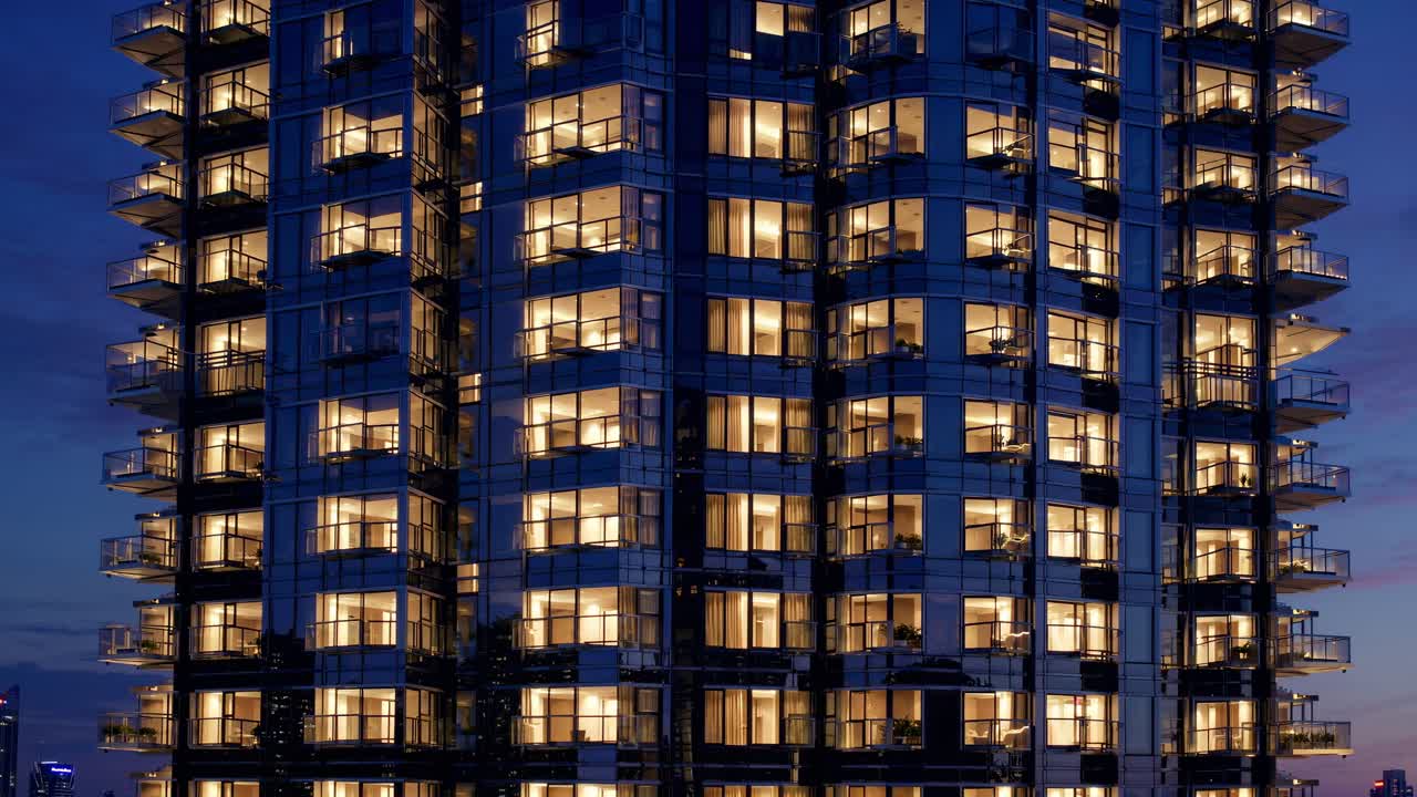 Warm lights emanating from apartment windows create a cozy atmosphere against the backdrop of the Singaporean twilight in a modern residential tower