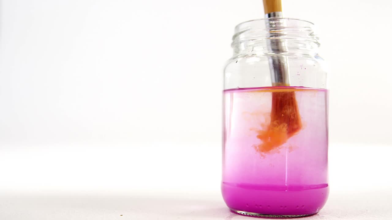 오렌지색 페인트를 물에 담그는 페인트 브러시