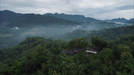 punthuk setumbu tourist spot with sunrise morning fog in bali magelang mountains, aerial orbit