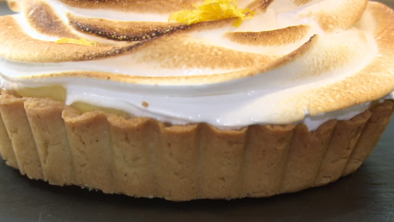 Close up of a lemon meringue tart with floral garnish