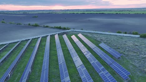 drone orbit tilt-up reveal shot of solar panels during sunset with colorful sky