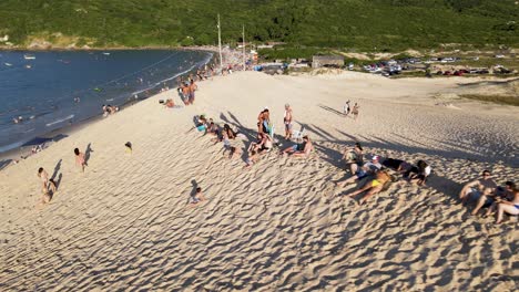 Luftdrohnenszene-Mit-Strand-Und-Menschen,-Die-Den-Sonnenuntergang-Auf-Den-Dünen-Genießen-Und-Sich-Im-Sand-Auf-Den-Dünen-Von-Florianópolis,-Brasilien,-Amüsieren