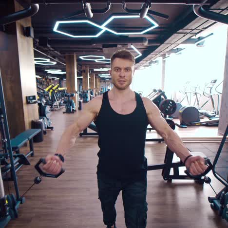 athletic guy training muscles on a modern simulator. portrait of handsome sportsman in modern gym. athlete exercises hard concentrated working at his perfect body