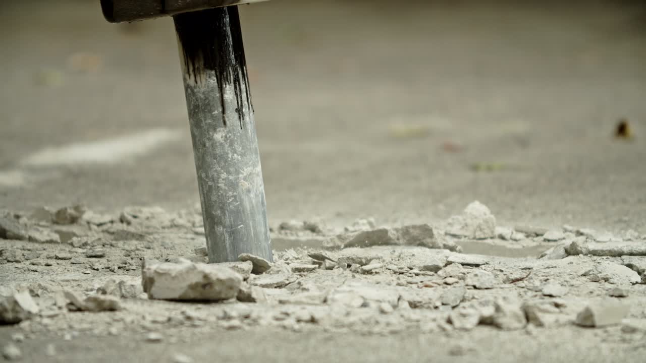 Close-up of excavator hydraulic arm rock breaker working on concrete road with sound